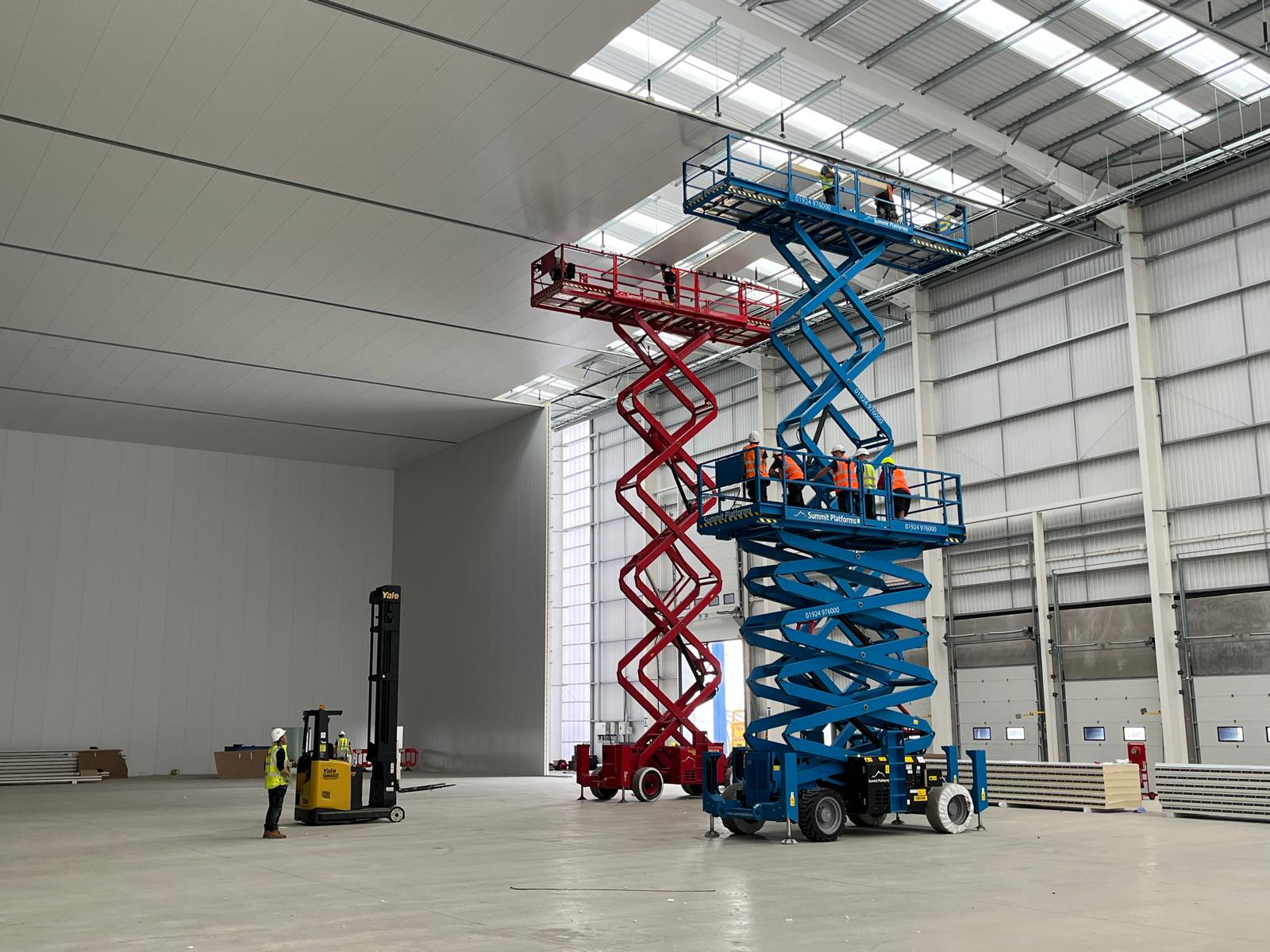 Scissor lifts at height during large-scale insulated panel installation